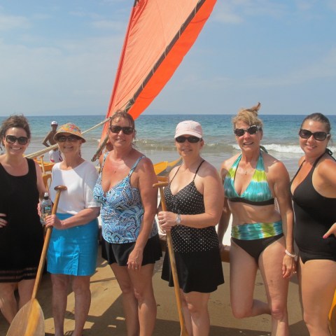 a group of people standing on a beach posing for the camera